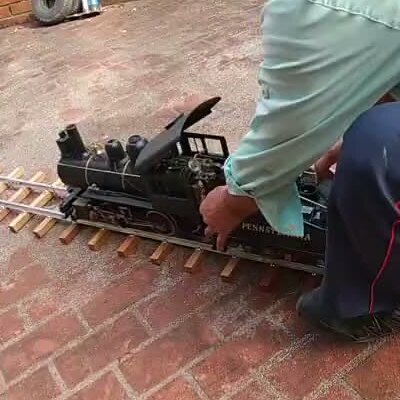 自作の蒸気機関車を線路で走らせているところ